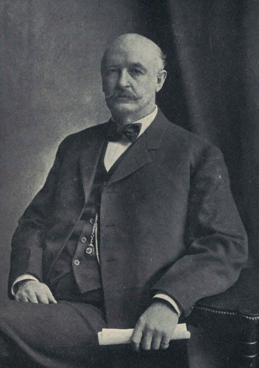 A formal portrait of David Patterson Hatch, seated in a suit with bow tie, holding a rolled paper.